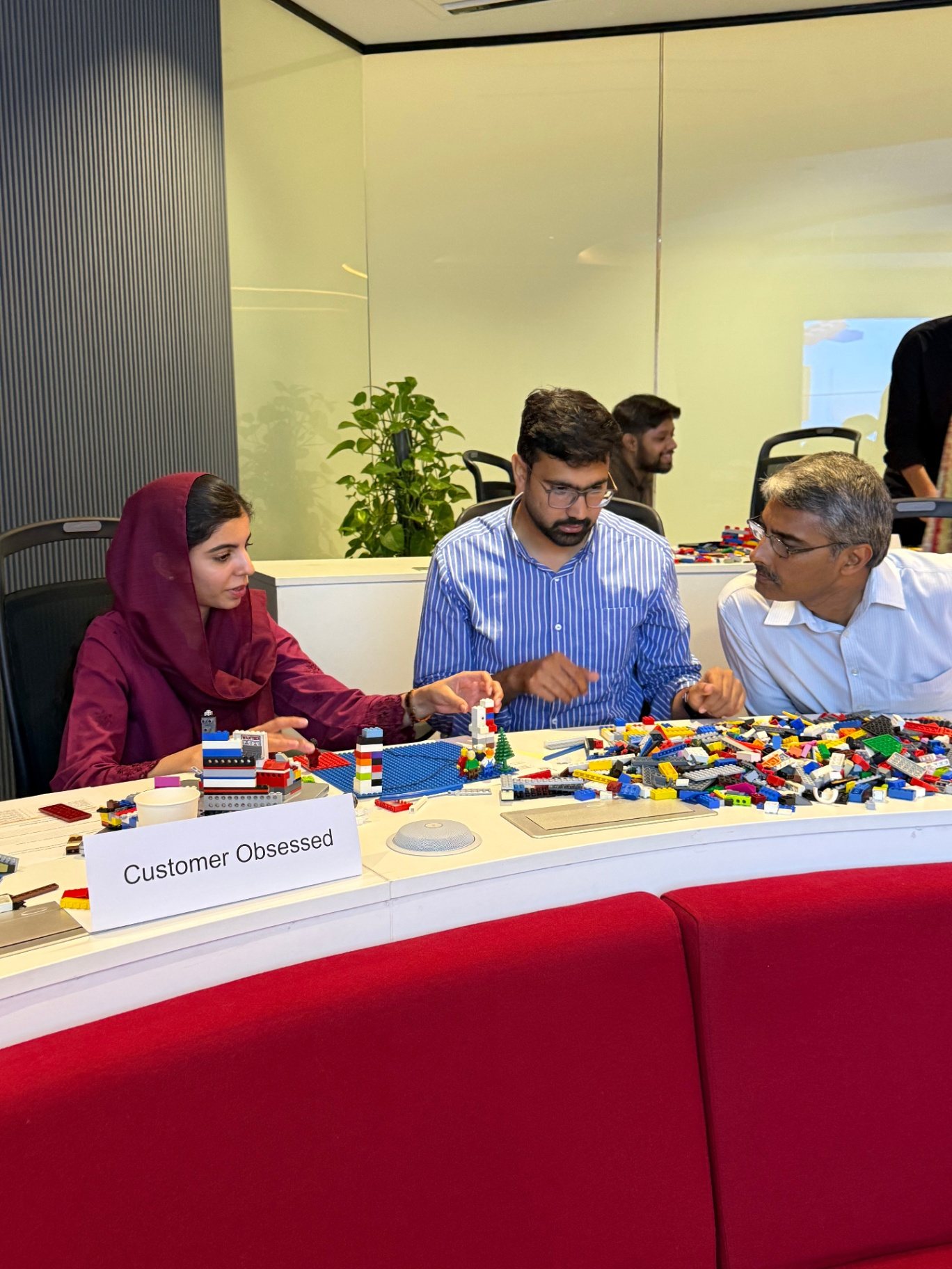 Small group gathered around a shared values table, discussing how their individual LEGO models connect